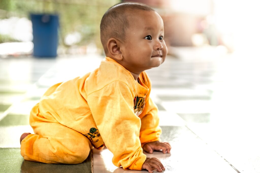 It's a baby crawling and looking at something curiously.